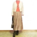 アーモンドプードル色のショートカーディガンに光沢プリーツスカートを合わせた大人可愛い冬コーデ