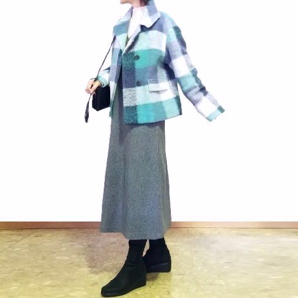 明るいブルーチェックのショートコートをグレーのAラインジャンパースカートに羽織った上品コーデ