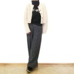 ロゴ入り黒ニットとチェックパンツにオートミールのケーブルカーディガンを羽織った都会的なデイリーコーディネート